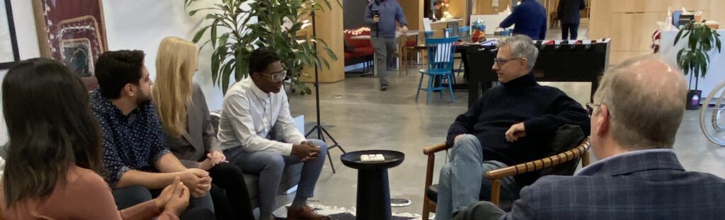 Executive leadership coach facilitating a small group coaching session in a collaborative workspace.
